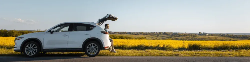 man sitting in car trunk enjoying view of sunset